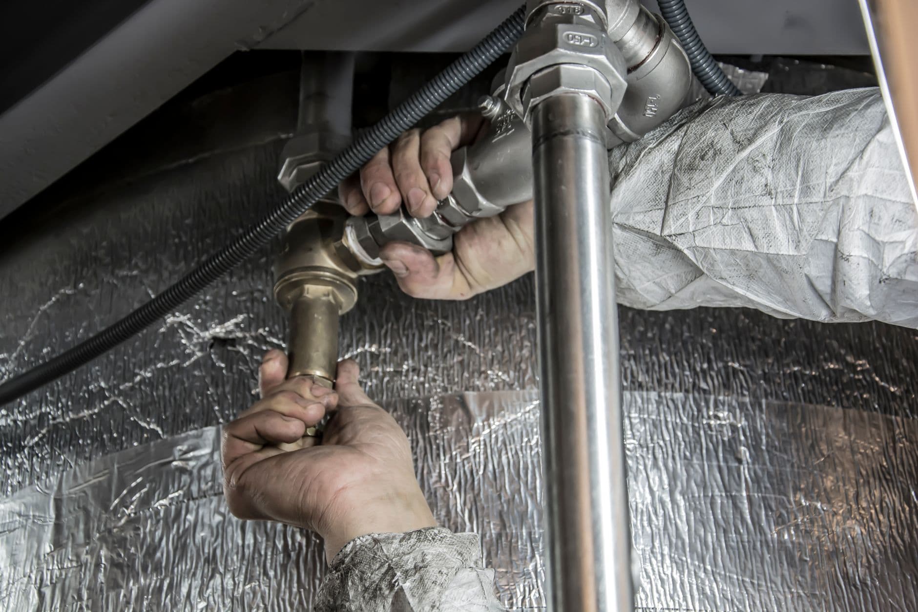 Plumber repairing pipes under a sink